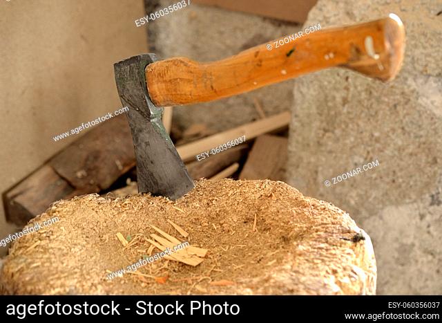 Ax in a wooden block with logs in the background