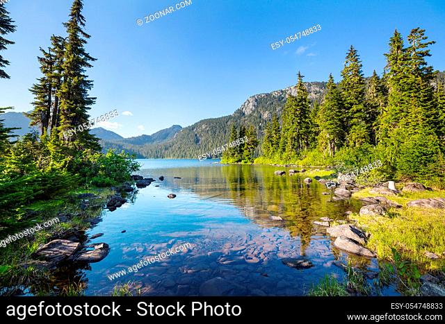 Serene scene by the mountain lake in Canada with reflection of the rocks in the calm water