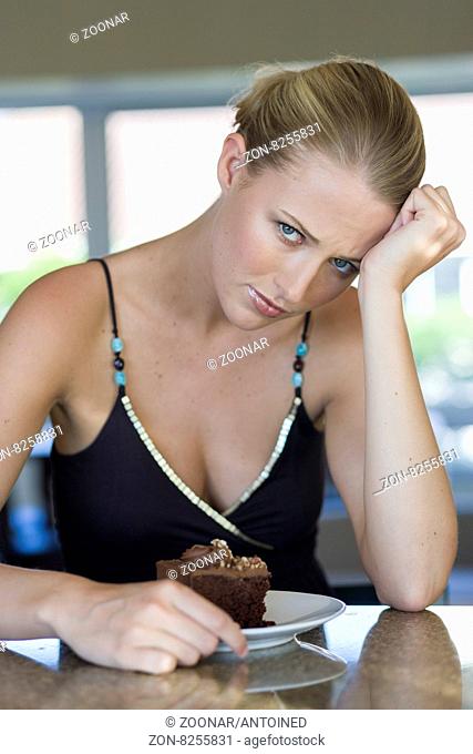 Young blond woman with chocolate cake indoors