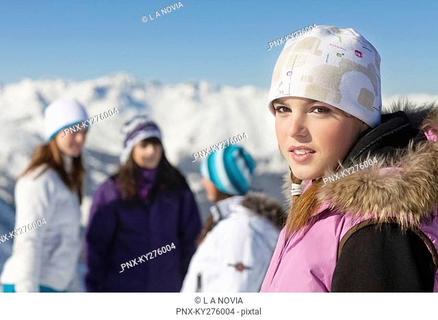 Teenage girl in ski clothes looking at camera, friends in background