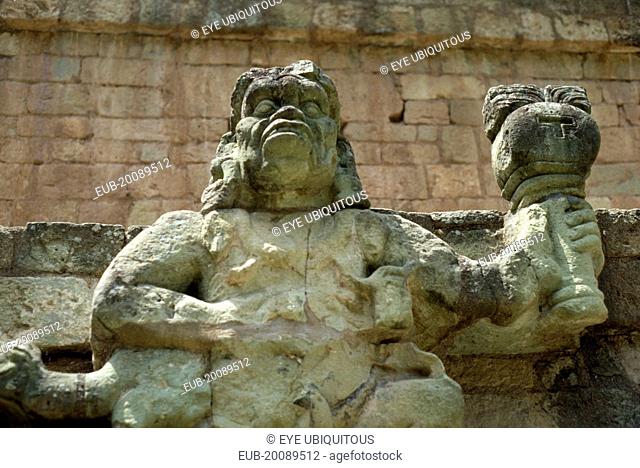 Site of ancient Mayan ruins. Detail of statue of figure holding burning torch
