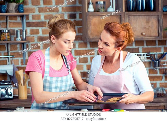 Mother and her teenage daughter making Christmas cookies in kitchen