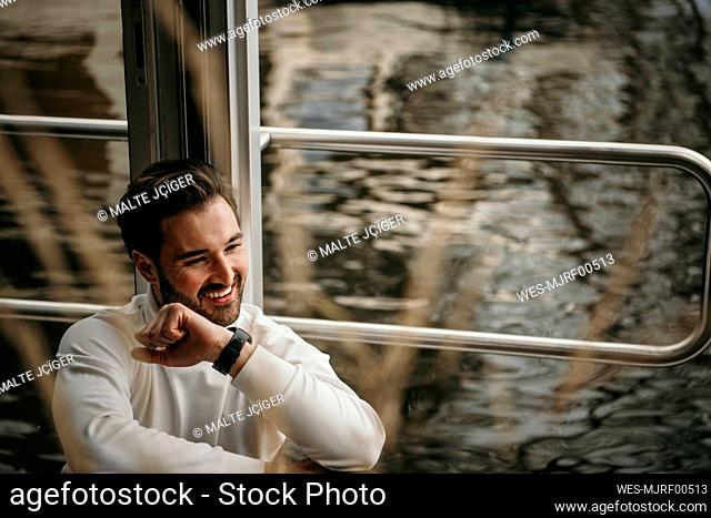 Smiling man leaning on railing in houseboat