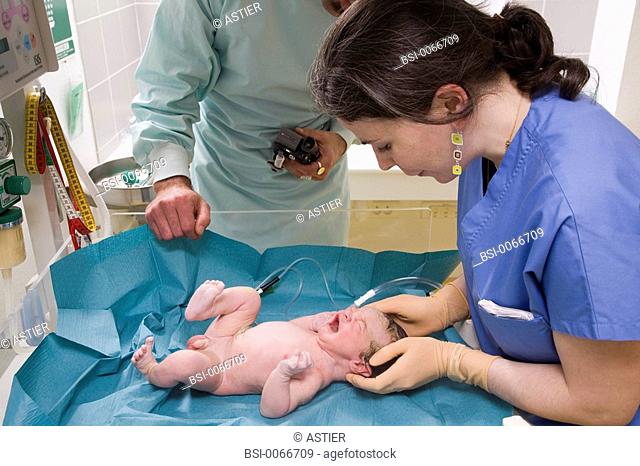 Photo essay at the maternity of Saint-Vincent de Paul hospital, Lille, France. The child care aid is taking care of the newborn baby under the eye of the father