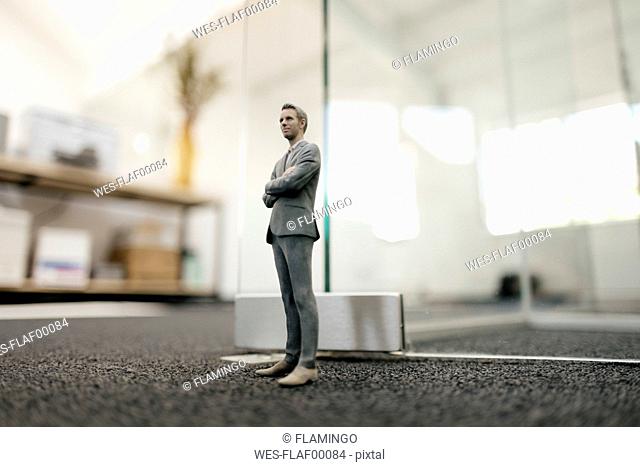 Businessman figurine standing in front of glass wall in office
