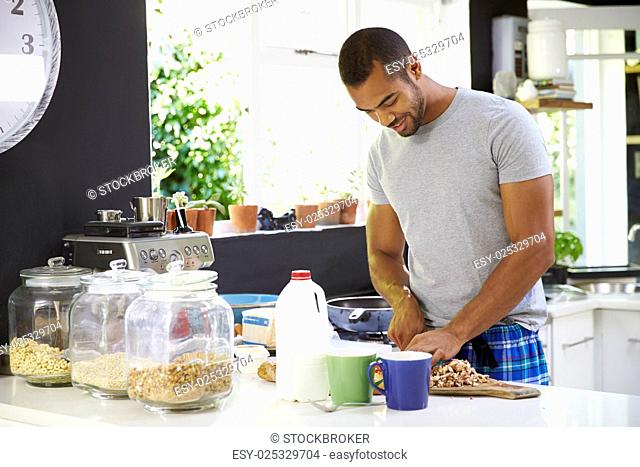 Young Man Wearing Pajamas Preparing Breakfast In Kitchen
