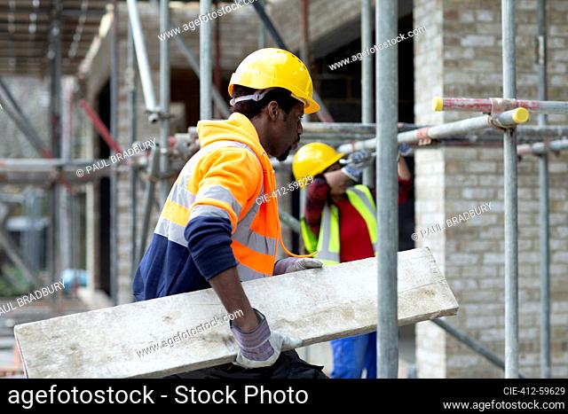 Construction worker carrying wood at construction site