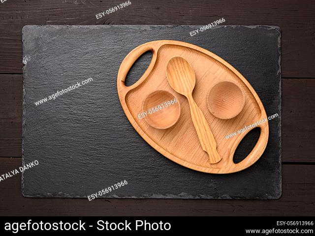 empty oval brown wooden tray board on a black background, top view