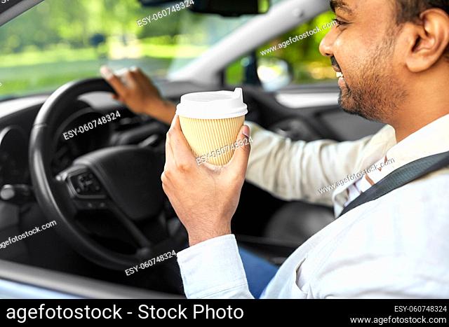 happy indian man or driver with coffee driving car