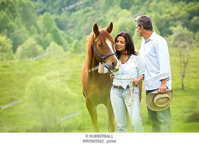 man and a woman standing with a horse