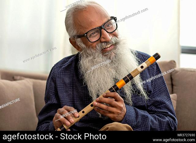 A HAPPY OLD MAN LOOKING AWAY WITH FLUTE IN HAND