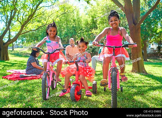 Portrait carefree sisters riding bikes in sunny summer park