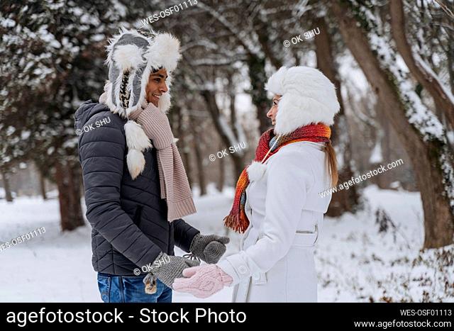 Happy young man with woman standing at park in winter
