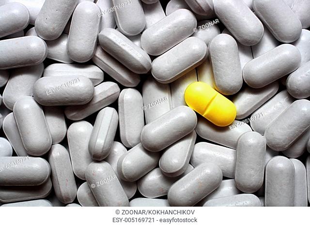 one yellow pill on grey pills