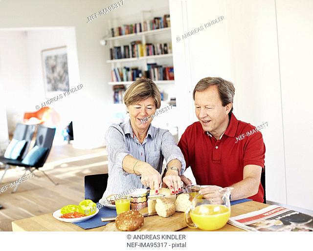 Mature couple preparing breakfast at table