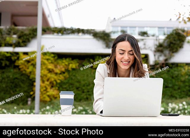 Smiling businesswoman working on laptop in park