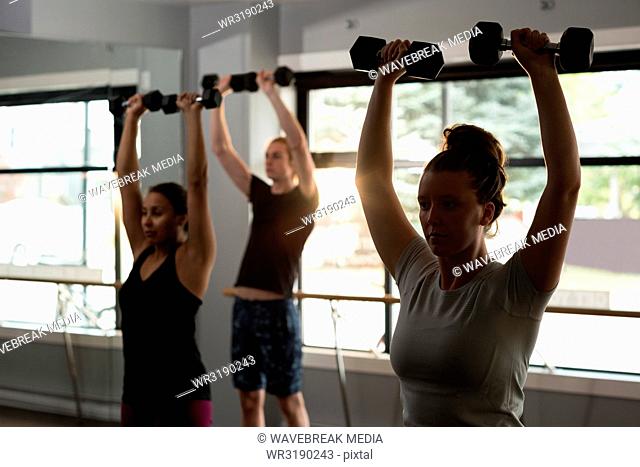 Trainer assisting women in exercising with dumbbells