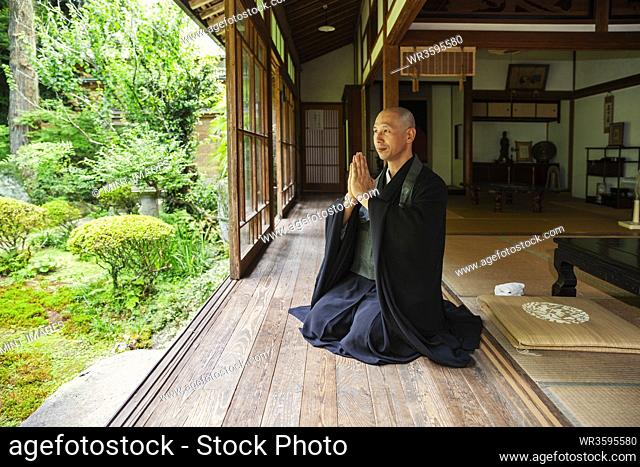 Buddhist priest kneeling in Buddhist temple, praying
