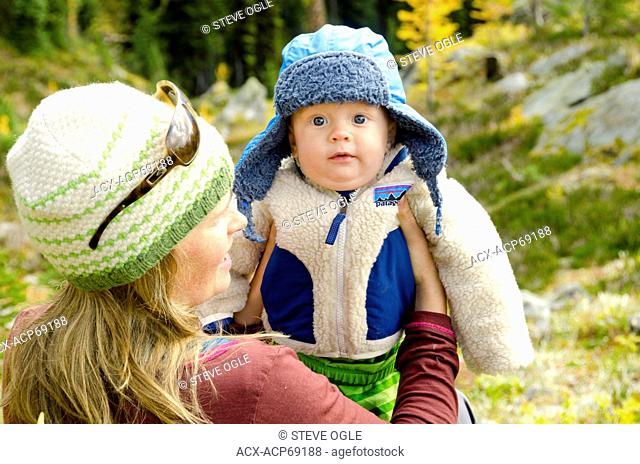 A boy is juggled by his mom while fall hiking in the Purcell Mountains near Nelson, British Columbia