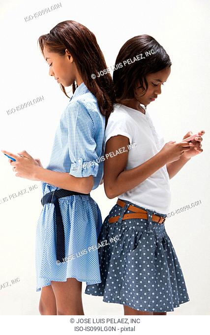 African American sisters using cellphones, studio shot