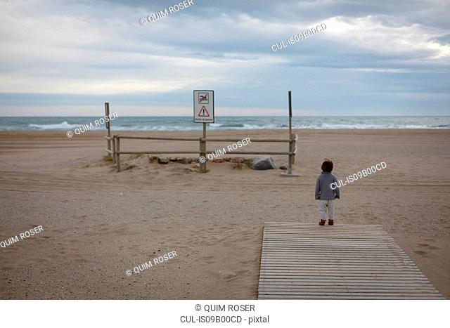 Girl on beach looking away at ocean
