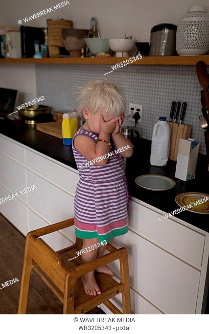 Baby girl standing on chair in kitchen