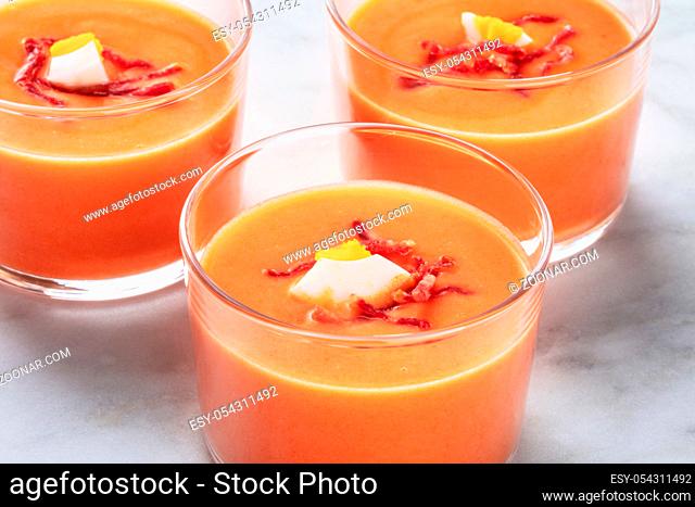 Salmorejo, Spanish cold tomato and bread soup, in glasses on a marble background, close-up shot