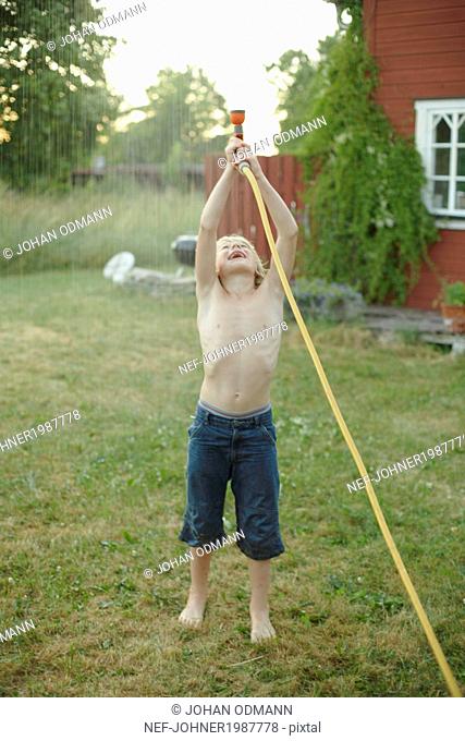 Boy playing with garden hose in garden