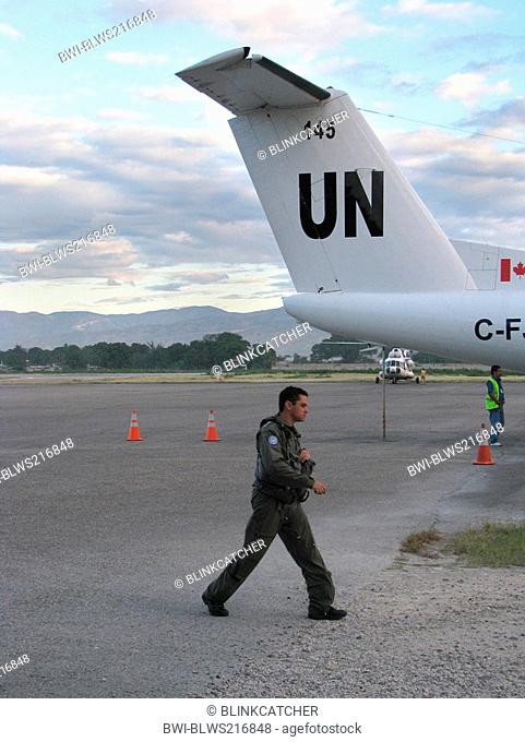 Pilot in battle dress passes aircraft of the 'United Nations Stabilisation Mission in Haiti', Haiti, Provine de l'Ouest, Port-Au-Prince