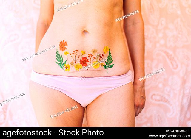 Woman in underwear showing Caesarean scar with flowers tattoo