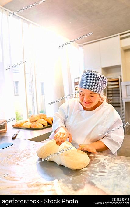 Smiling young woman with Down Syndrome kneading dough
