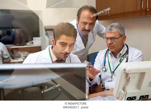 Doctors looking at CT scan on computer screen