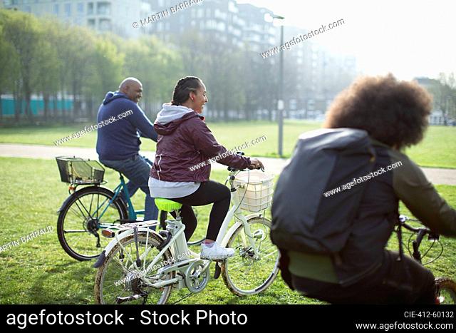 Happy family riding bicycles in sunny urban park grass