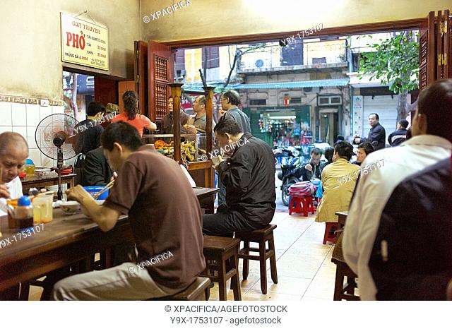 The interior of a famous pho shop in Vietnam filled with people enjoying the traditional noodle dish