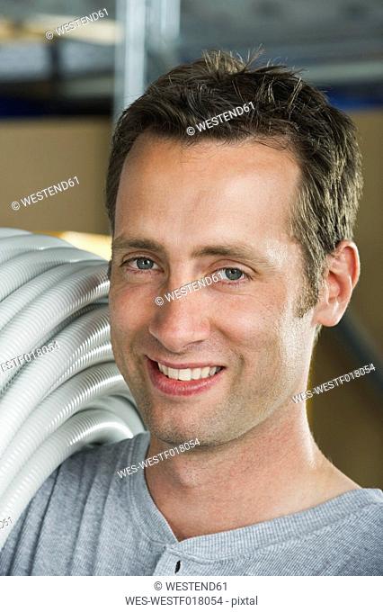 Germany, Bavaria, Munich, Manual worker carrying plastic hose, close up