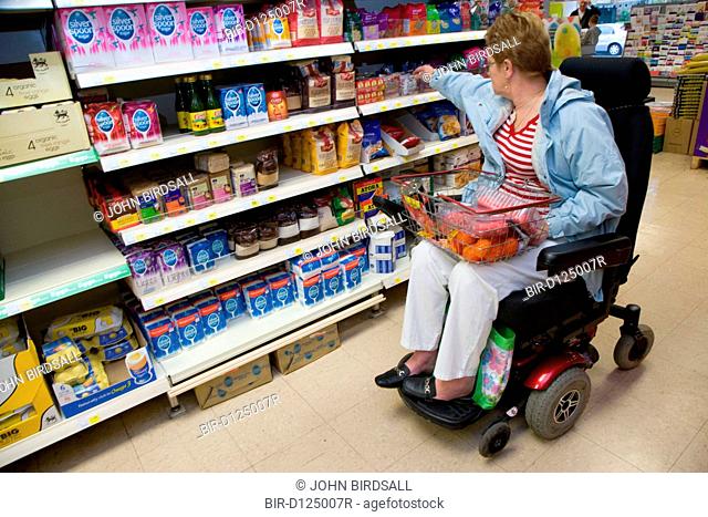 Older woman wheelchair user shopping for food in a supermarket