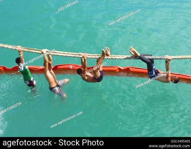 boys play on ship's rope, Hakahau harbor, Ua Pou, Marquesas, French Polynesia