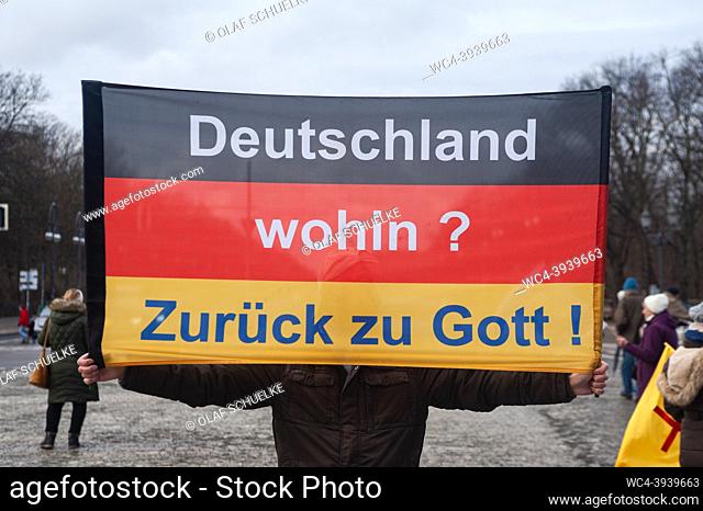 Berlin, Germany, Europe - A man holds a German flag reading Deutschland wohin? Zurueck zu Goot! (Germany where to? Back to God!) at the Platz des 18 Maerz...