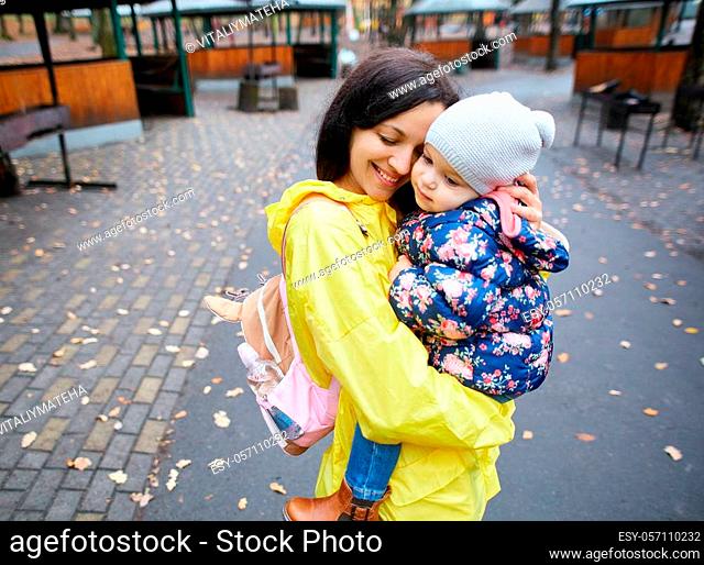 Happy mother with daughter walking in the autumn park. Loving young mother embracing cute kid daughter, enjoying time together outdoors at weekend