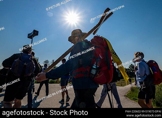 dpatop - 02 June 2022, Bavaria, Regensburg: A pilgrim carries a wooden cross during Germany's largest foot pilgrimage. Until Saturday