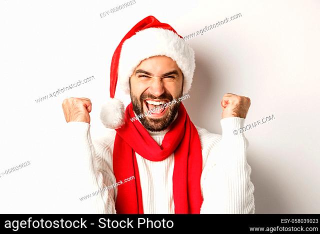New Year party and winter holidays concept. Close-up of excited man in Santa hat rejoicing, winning or celebrating in Santa hat