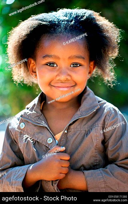 Outdoor portrait of cute African girl wearing brown jacket