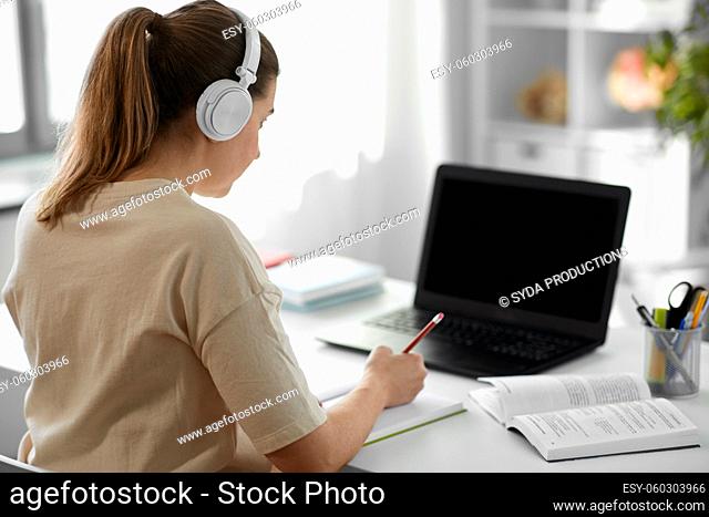 student woman in headphones with laptop and book