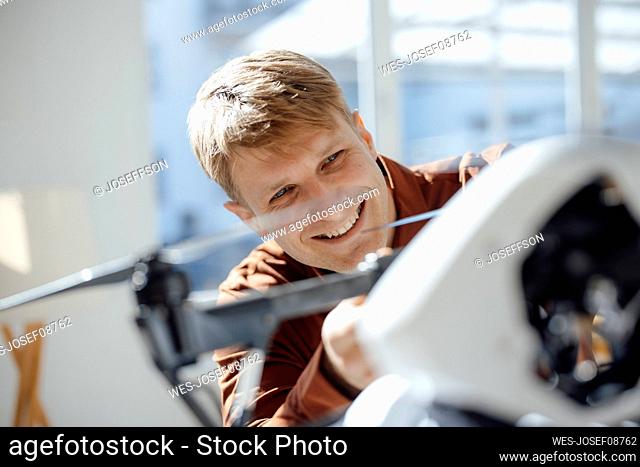 Happy businessman examining drone in office