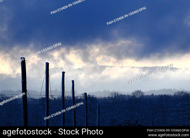 06 April 2021, Baden-Wuerttemberg, Ravensburg: Snow clouds cover the sky, while a transmission tower on a mountain can be seen in the background
