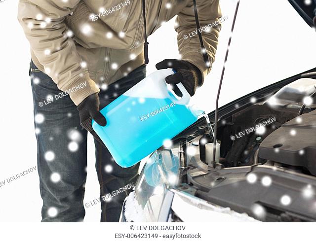 transportation, winter, people and vehicle concept - closeup of man pouring antifreeze into car
