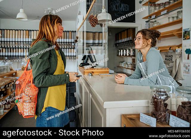 Female customer talking to clerk in zero waste store during pandemic