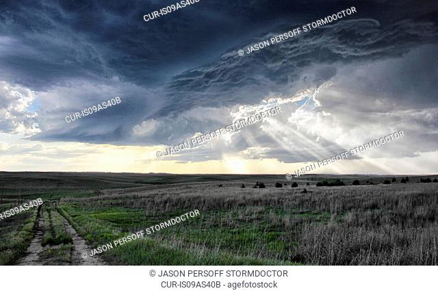 Crepuscular rays forming under shelf cloud, rotating mesocyclone in background, Sidney, Nebraska, USA