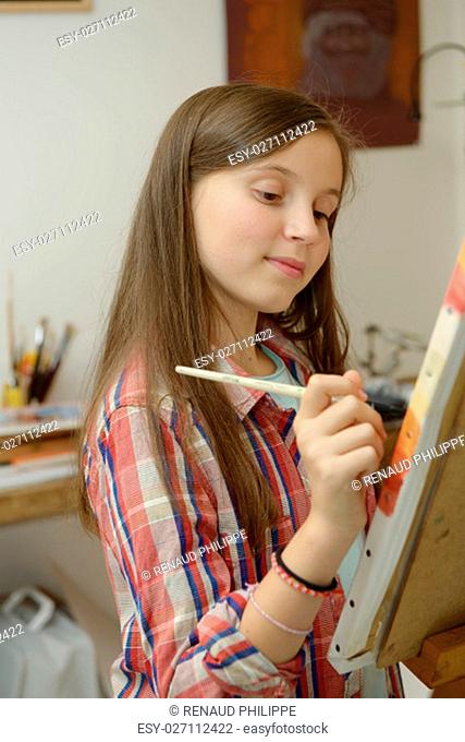 Smiling young artist girl teen painting a canvas