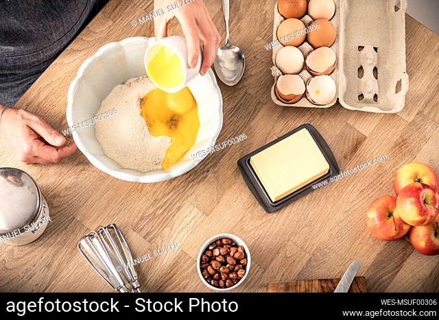 Woman hand putting egg yolk in bowl while standing at kitchen island